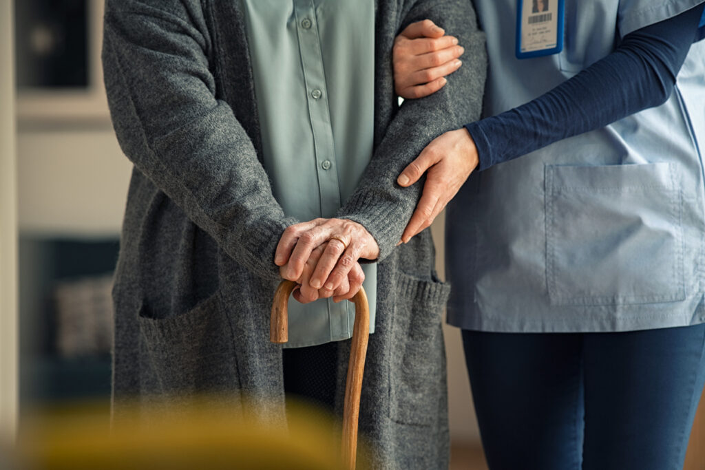 Nurse assisting senior with walking cane How to Recognize When It’s Time for Memory Care | AVIVA Granbury Senior Living